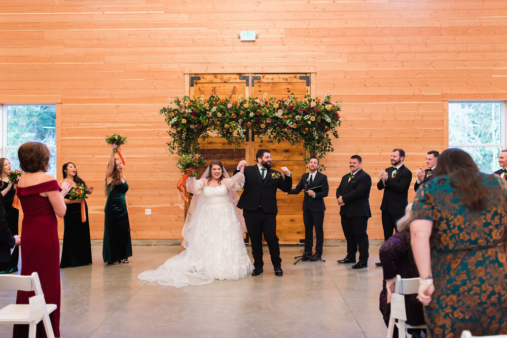Couple celebrating with arms raised at a candlelit winter ceremony
