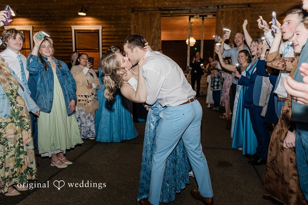 Couple kissing during a phone-light send-off outside the barn